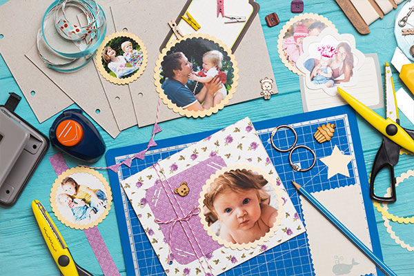 Materiali per scrapbooking con foto, forbici, cartoncini e accessori decorativi